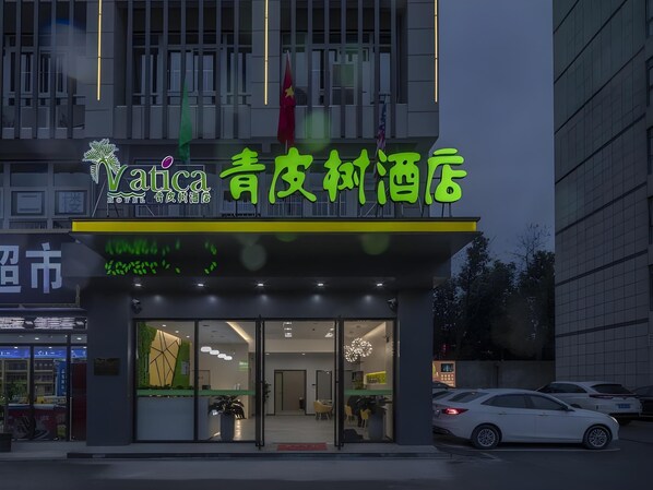 Un hotel con fachada moderna, amplios ventanales de vidrio y un letrero de neón.