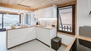 Una cucina moderna con mobili bianchi, soffitto in legno e un'ampia finestra vista panoramica.