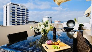 A rooftop terrace with a table set for dining, a grill, and a view of the city skyline. - Premium w terrace. 2 min 2 beach, 90 sqm, Algarve (Quarteira)
