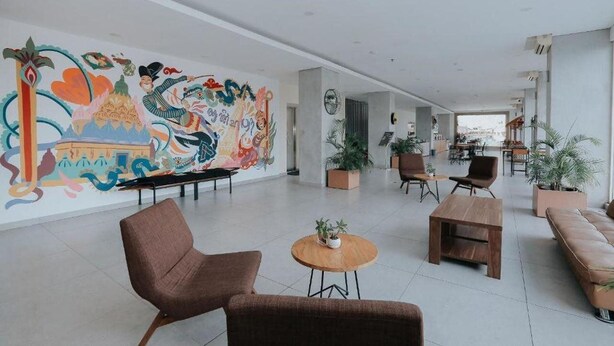 A spacious lobby with a colorful mural, comfortable seating, and potted plants. - Arte Yogyakarta (Yogyakarta)