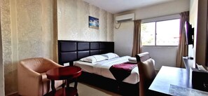 Une chambre d’hôtel avec un lit, un bureau, une chaise et une petite table.