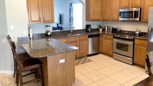 Una cocina con encimeras de granito, armarios de madera, electrodomésticos de acero inoxidable y una isla integrada con asientos.