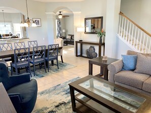 A spacious living room with a dining area, a staircase, and a kitchen in the background. - Windsor Hills Resort! 6 Bedroom House, 2 miles to Disney, Private Pool & Spa🏝 (Kissimmee)