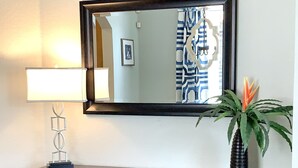 Una consola de madera oscura con un espejo encima, una lámpara a la izquierda y jarrones decorativos abajo.