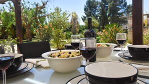 Un espacio al aire libre para comer con una mesa preparada para una comida, rodeado de follaje y árboles.