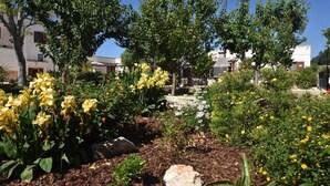A garden with yellow flowers, trees, and a stone structure. - Mela  Masseria Giulio (Masseria Don Giulio Francavilla Fontana)
