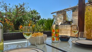A table set for two with wine glasses, a bowl of chips, and a decorative bottle. - Mela  Masseria Giulio (Masseria Don Giulio Francavilla Fontana)