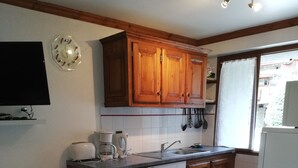 A kitchen with wooden cabinets, a sink, and a dining table with a patterned tablecloth.