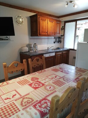 Uma cozinha com armários de madeira, uma pia e uma mesa de jantar com toalha de mesa estampada.