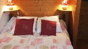 A wooden-paneled room with a bed, two bedside lamps, and a decorative heart garland.