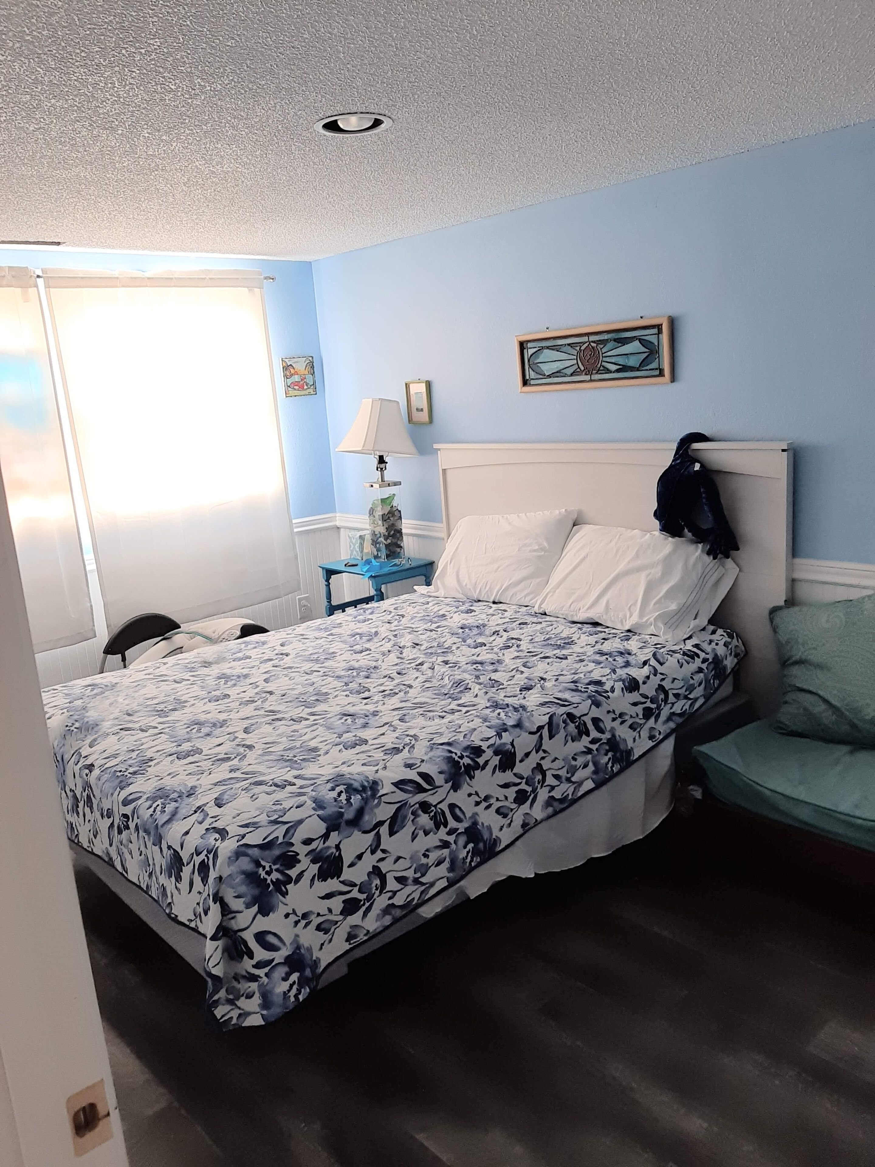 A bedroom with a bed, a nightstand, a lamp, and a window.
