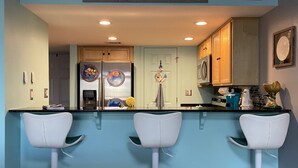 A kitchen with a blue theme, featuring a refrigerator, stove, and bar stools. - Sunshine & Beach Views at 2046 Beach Blvd (Biloxi)