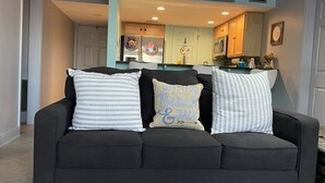 A dark grey sofa with three decorative pillows in a living room. - Sunshine & Beach Views at 2046 Beach Blvd (Biloxi)