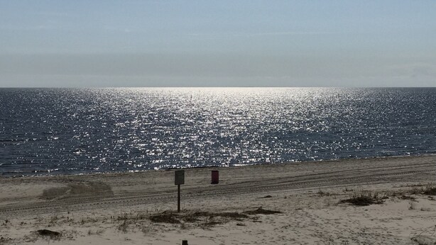 A beach with a sandy shore and a sign in the foreground. - Sunshine & Beach Views at 2046 Beach Blvd (Biloxi)
