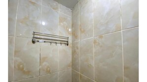 A bathroom with beige marble tiles and a metal towel rack.