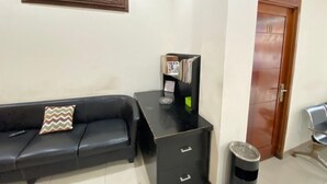 A room with a black leather sofa, a wooden door, a black filing cabinet, and a wall-mounted decorative panel.