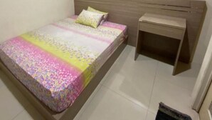 A bedroom with a bed, a bedside table, and a window with curtains.