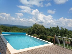 A rectangular swimming pool with a wooden deck and a blue cover on one side. - Renovated house with view and heated pool (Badefols-d'Ans)