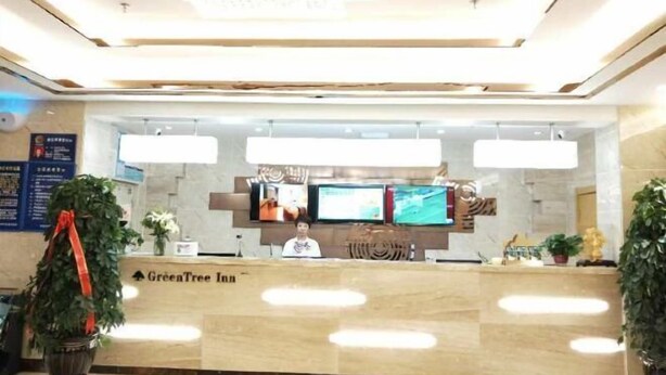 A reception area with a marble counter, multiple monitors, and a sign for GreenTree Inn. - Greentree Inn Business Hotel (Shenyang Huaxiang Shengjing Hospital) (Shenyang)