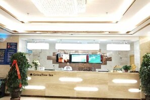 A reception area with a marble counter, multiple monitors, and a sign for GreenTree Inn. - Greentree Inn Business Hotel (Shenyang Huaxiang Shengjing Hospital) (Shenyang)