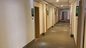 A hotel hallway with doors marked by numbers, carpeted floors, and a ceiling with recessed lighting. - Greentree Inn Business Hotel (Shenyang Huaxiang Shengjing Hospital) (Shenyang)