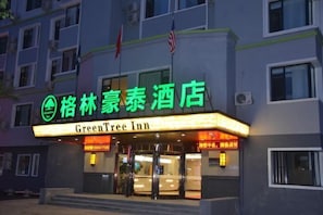 Entrada de un hotel con un letrero de neón que indica que es el GreenTree Inn.