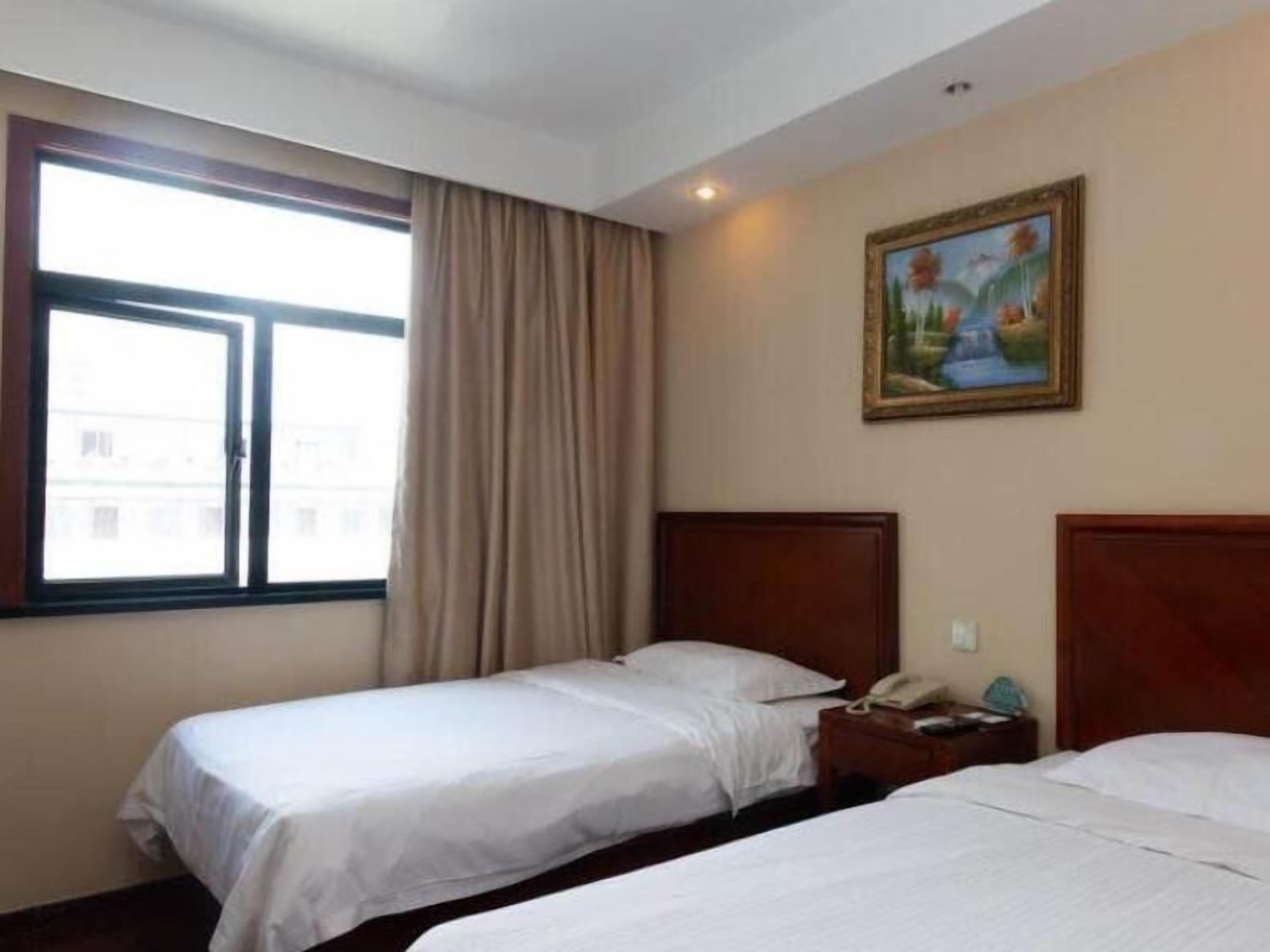 A hotel room with two single beds, a window with curtains, a painting on the wall, and a nightstand with a phone.