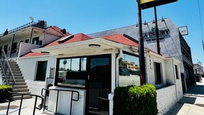 Un motel con techo rojo, una pequeña entrada y un letrero que dice 'Motel Vista'.
