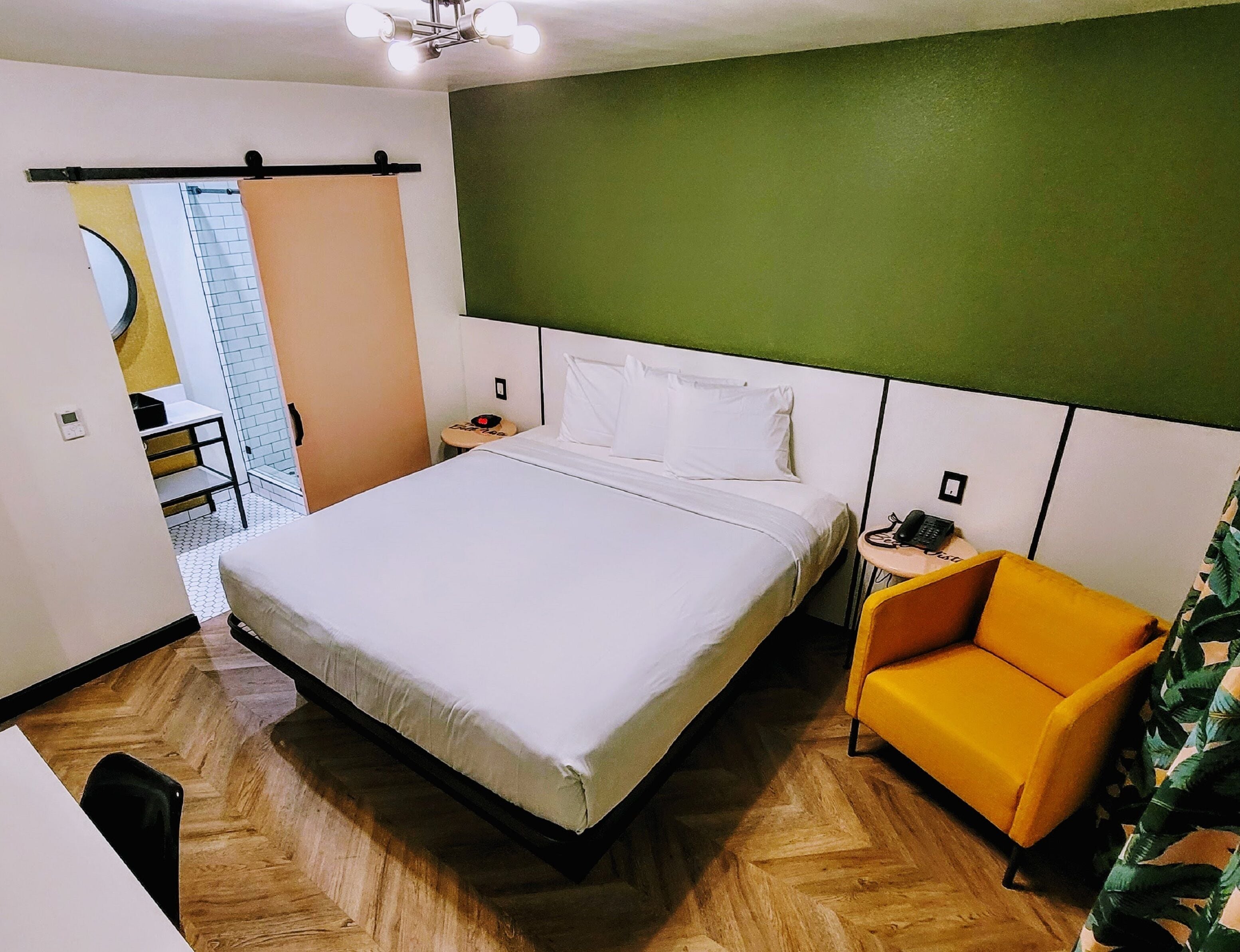 Habitación de hotel con una cama grande, una mesita pequeña, una silla y un teléfono.