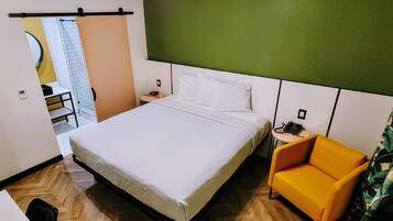 Habitación de hotel con una cama grande, una mesita pequeña, una silla y un teléfono.