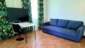 Una habitación con sofá, televisión, mesa y una silla.