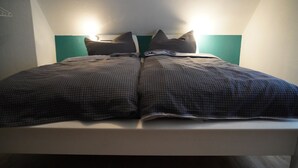 Un lit avec un cadre blanc et une tête de lit de couleur turquoise.
