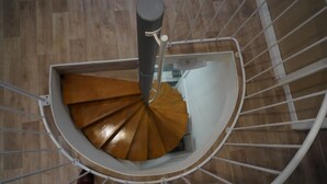 Un escalier en colimaçon avec une rampe en métal et des marches en bois.