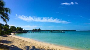 A beach with clear turquoise water, a sandy shore, and a pier extending into the water. - Hope Town's Top Rental: Beachfront sunsets, AC, free boat dock, & close to town! (Hope Town)
