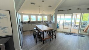 A spacious kitchen with a large island, a ceiling fan, and a view of the beach through the sliding glass doors. - Hope Town's Top Rental: Beachfront sunsets, AC, free boat dock, & close to town! (Hope Town)