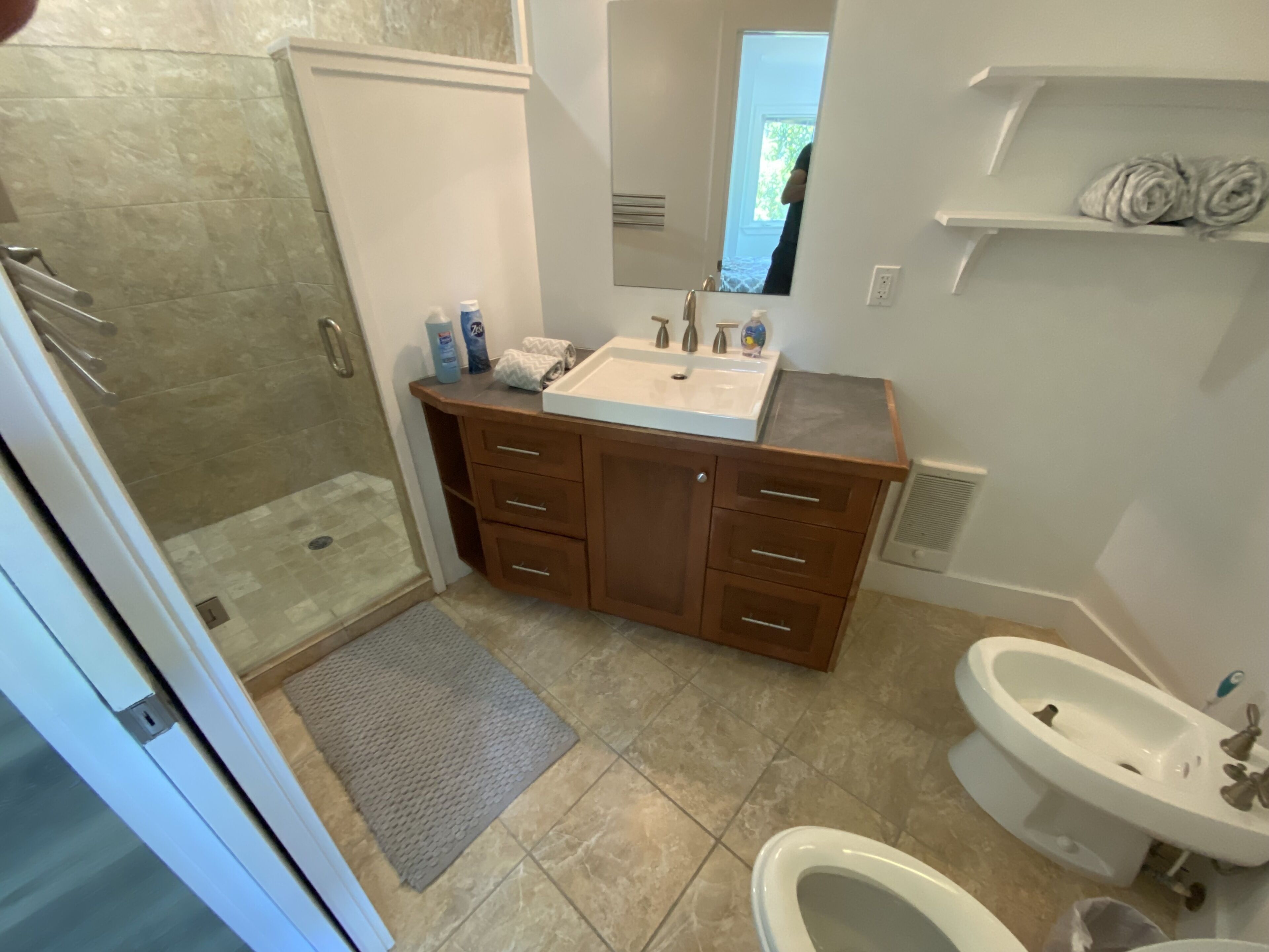 Ein Badezimmer mit bodengalerieartiger Dusche, einem Waschtisch und einem separaten Standwaschbecken.