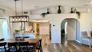 A spacious kitchen with a dining area, wooden flooring, and modern lighting fixtures. - Trendy Getaway + Pool, Spa, Game Room, Views (Lake Havasu City)