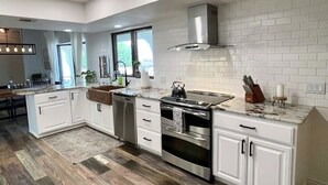 A modern kitchen with white cabinetry, stainless steel appliances, and a wooden floor. - Trendy Getaway + Pool, Spa, Game Room, Views (Lake Havasu City)