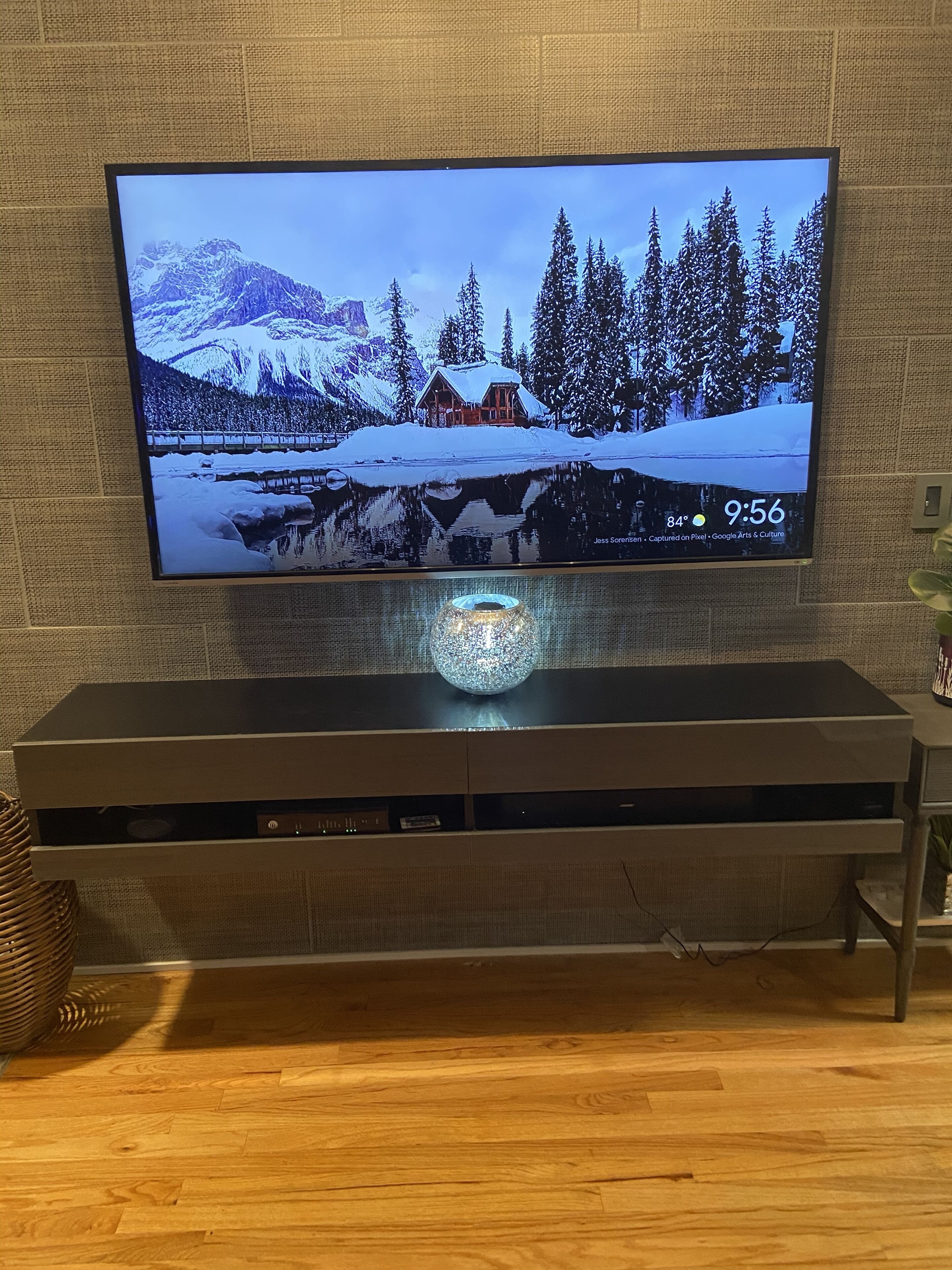 A flat-screen TV mounted on a wall above a wooden entertainment center.