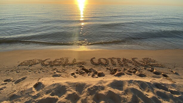 A beach with footprints and the words "Beach Lovers" written in the sand.