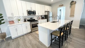 A modern kitchen with white cabinets, stainless steel appliances, and a central island with bar stools.