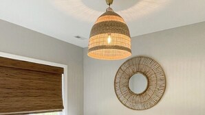 A bedroom with a large bed, a bedside table, a wall-mounted mirror, and a ceiling light fixture.