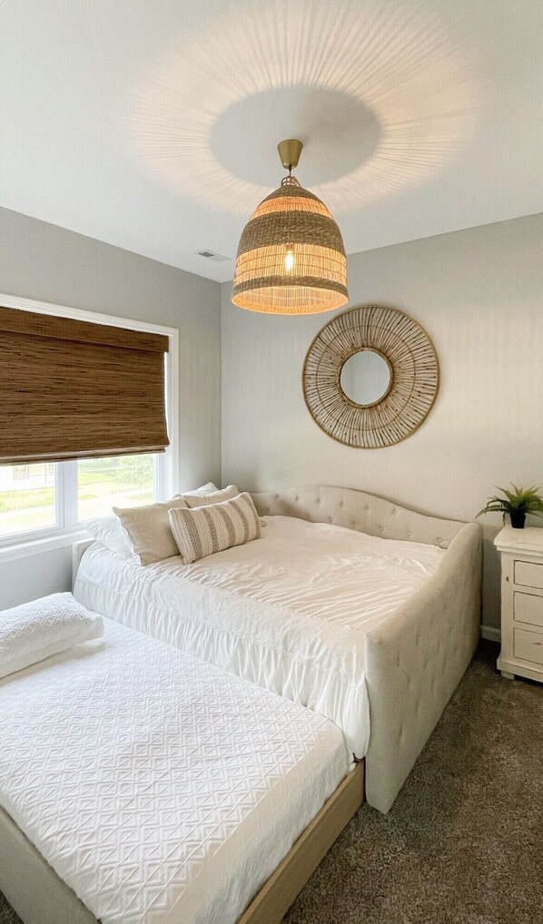 Une chambre à coucher avec un grand lit, une table de chevet, un miroir fixé au mur et un luminaire au plafond.