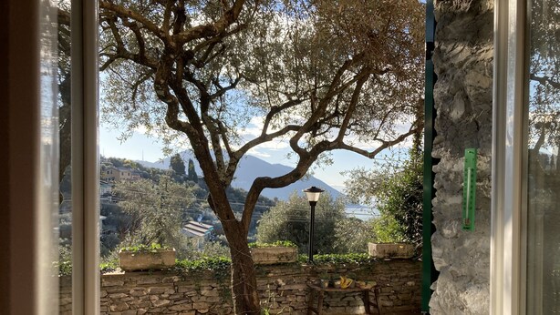 Eine Steinsäule, ein Baum und ein Blick auf eine gebirgige Landschaft durch ein Fenster.