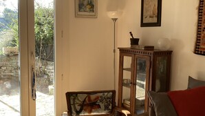 Ein Wohnzimmer mit einem Holzstuhl, einem Sofa, einer Glasschrank und einem Gemälde an der Wand.