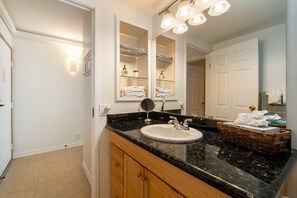 A bathroom with a sink, mirror, and towel rack. - Island Surf Resort, breathtaking ocean view, in the heart of the action (Kihei)