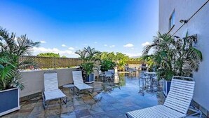 A rooftop patio with stone flooring, white metal lounge chairs, and potted plants. - Island Surf Resort, breathtaking ocean view, in the heart of the action (Kihei)