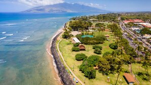 An aerial view of a coastal area with a beach, a road, and buildings. - Island Surf Resort, breathtaking ocean view, in the heart of the action (Kihei)