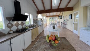 A spacious kitchen with a central island, a dining area, and a TV mounted on the wall. - Rural House Altaret (Callosa d'en Sarrià)