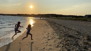 A beach scene with two children running along the shore during sunset. - Wellfleet Woodlands Escape - Privacy in the Pines! (Wellfleet)